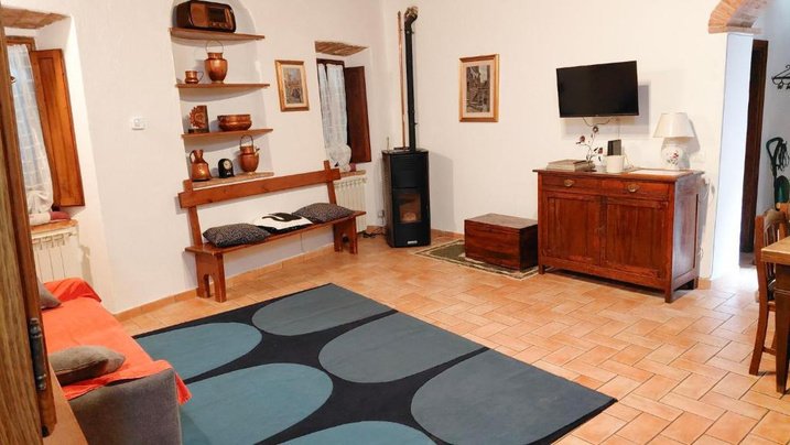 Il soggiorno con divano letto, tappeto blu e stufa