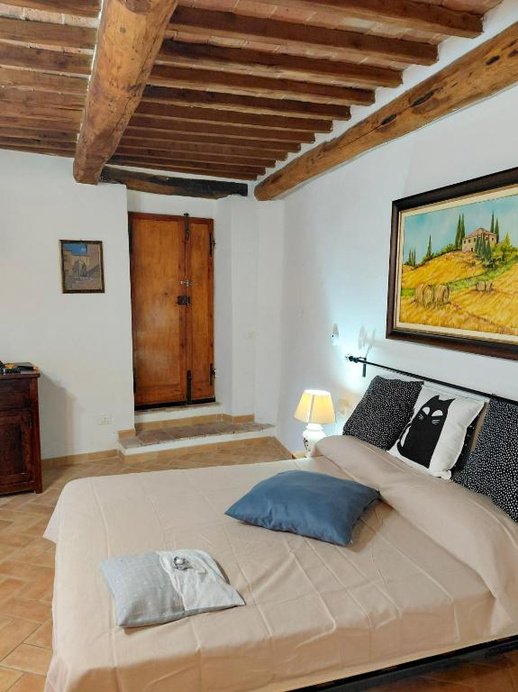 Letto matrimoniale sotto le travi a vista, con una porta antica in legno