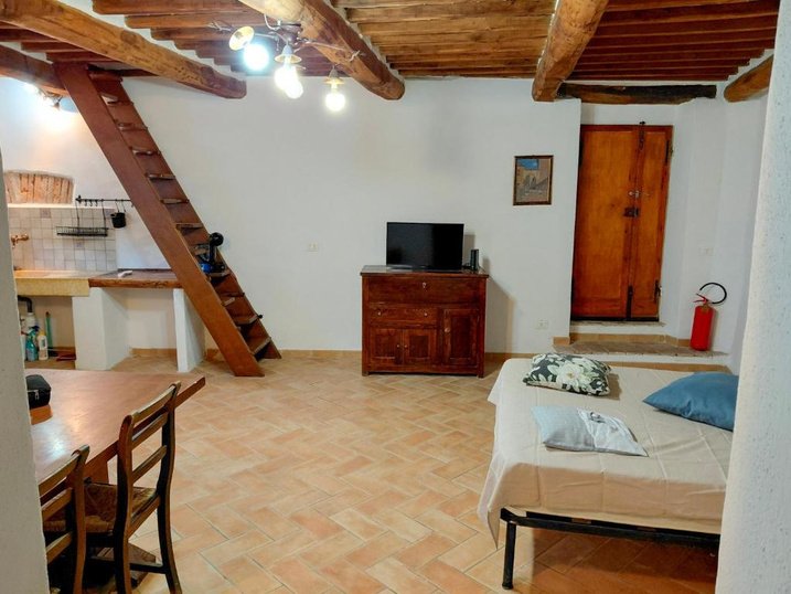 Open space con travi, scala in legno e angolo cottura
