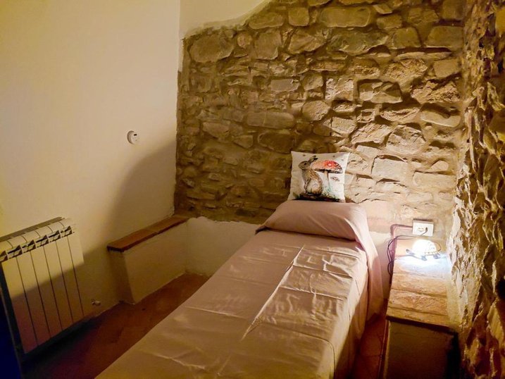 Letto singolo, muro in pietra e termosifone