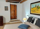 Letto matrimoniale sotto le travi a vista, con una porta antica in legno