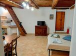 Open space con travi, scala in legno e angolo cottura