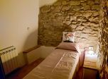 Letto singolo, muro in pietra e termosifone